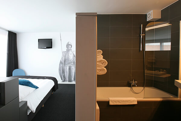 Inrichting van een hotelkamer waarbij de badkamer niet helemaal fysiek afgescheiden is